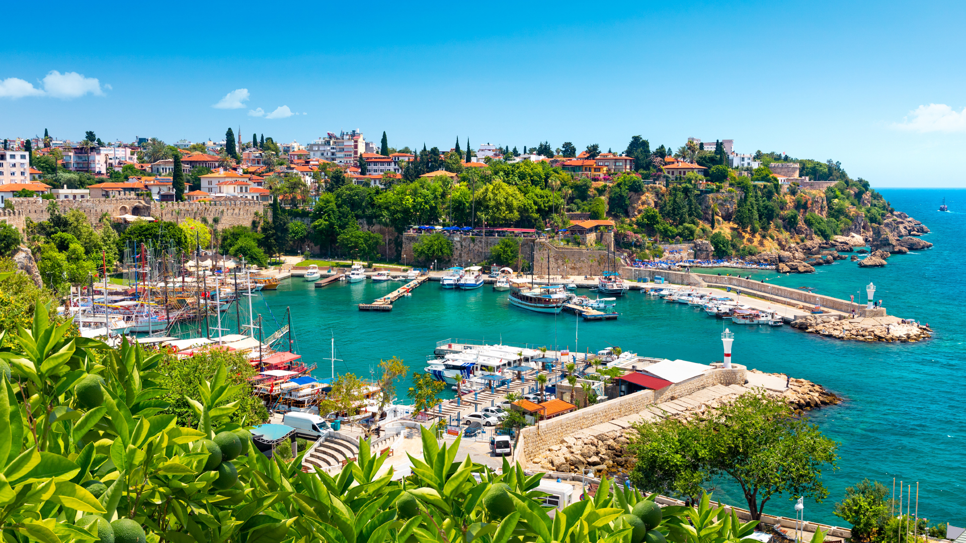 Antalya's old harbour seen from above, the marina ringed by ramparts and tile-roofed houses beside the Mediterranean