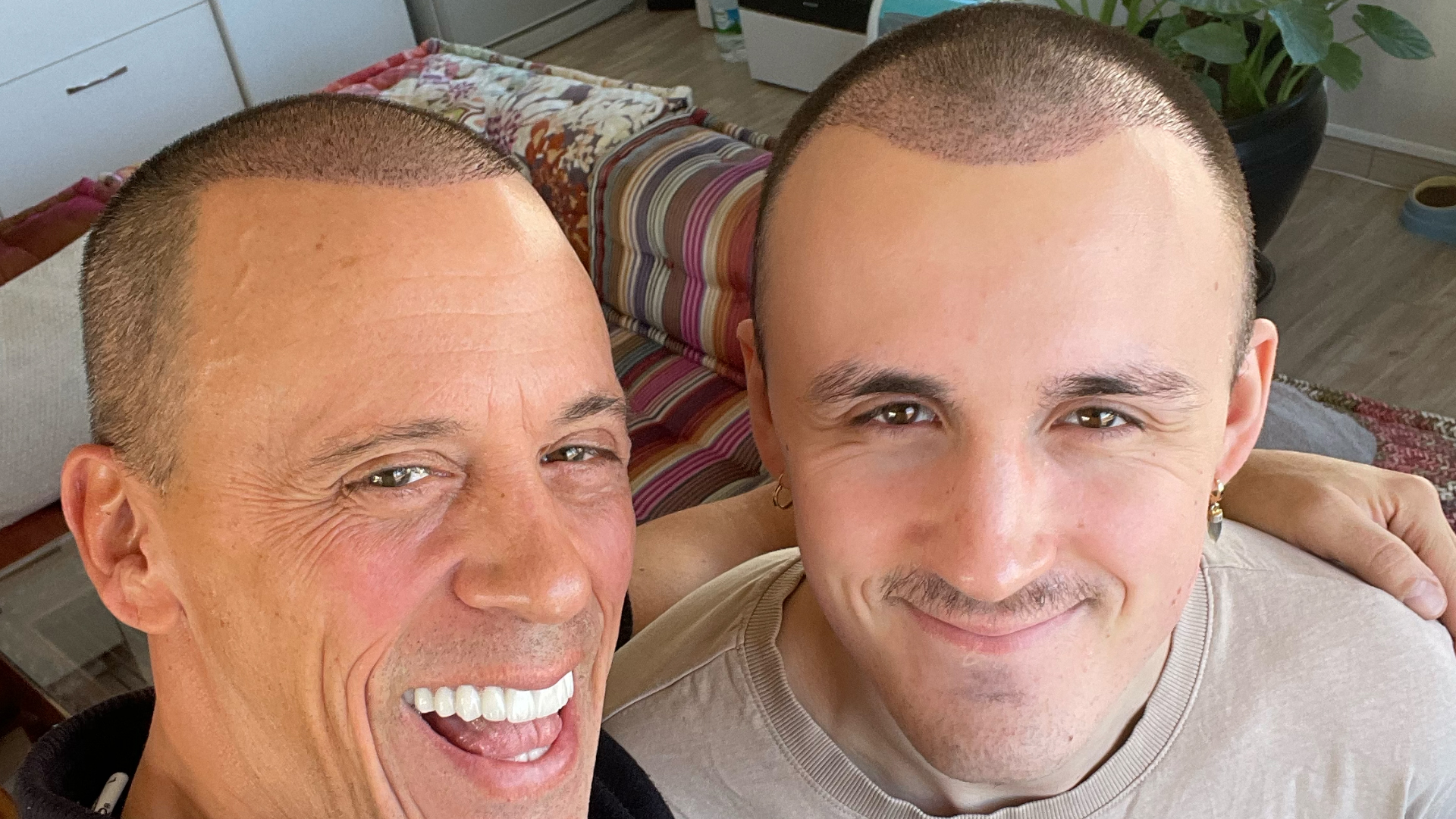 Deux hommes aux cheveux courts souriant côte à côte