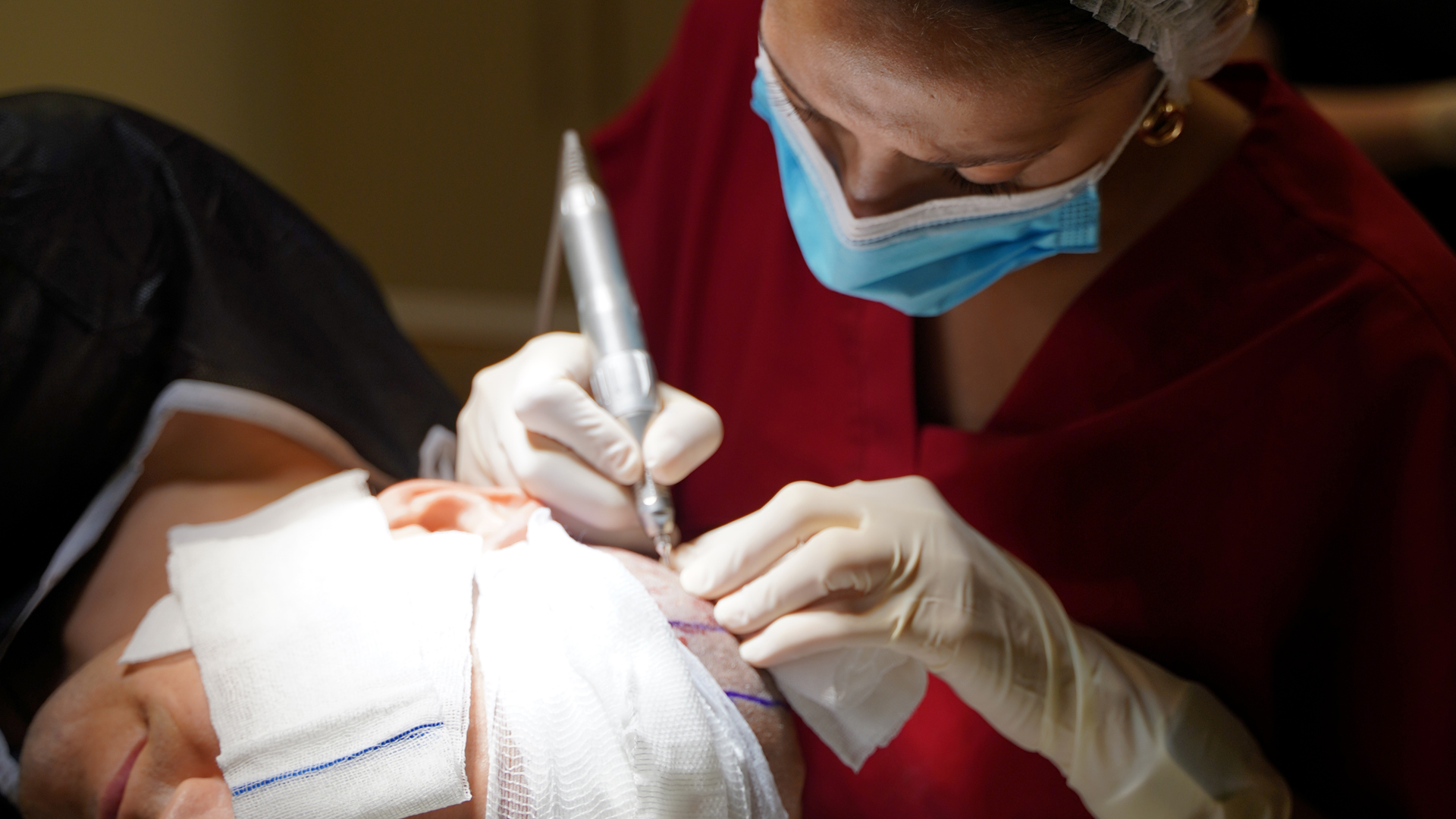 Professionnelle masquée manipulant un instrument près du cuir chevelu d’un patient
