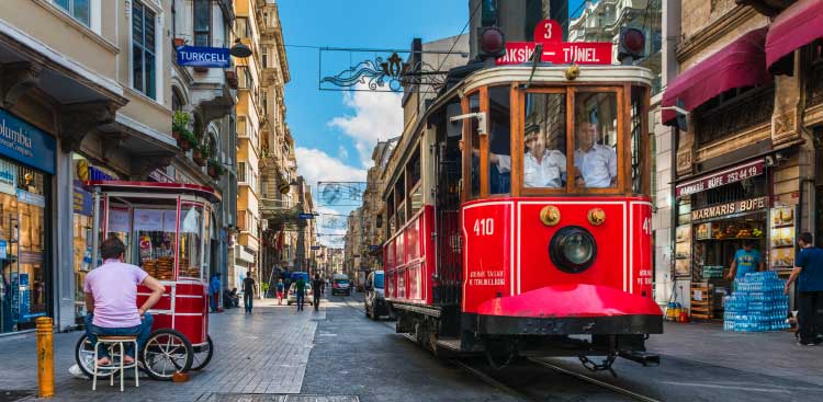 Tramway rouge « nostalgique » de l’avenue İstiklal, immeubles et devantures de commerces de part et d’autre de la voie