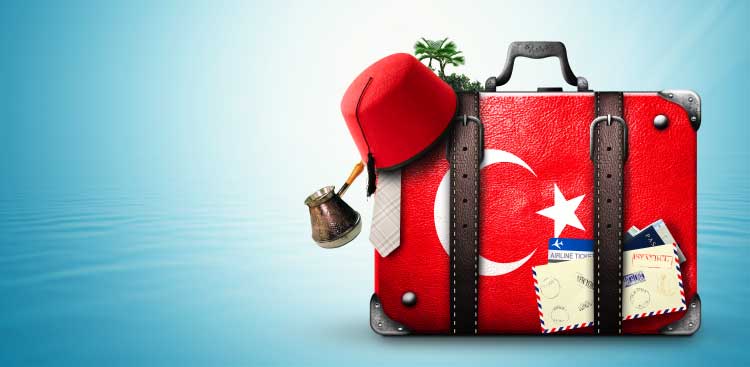 Valise rouge aux couleurs du drapeau turc, surmontée d’un fez, d’une cafetière à café turc et d’une carte d’embarquement, sur fond bleu