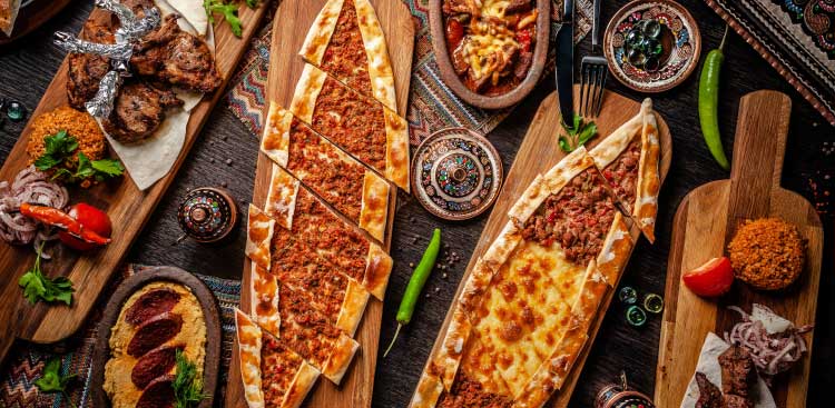 Plats turcs vus de dessus : pide, lahmacun, brochettes et mezzés disposés sur des planches en bois