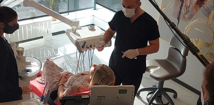 Marie lying in a dental chair during her treatment, with a practitioner and an assistant at her side