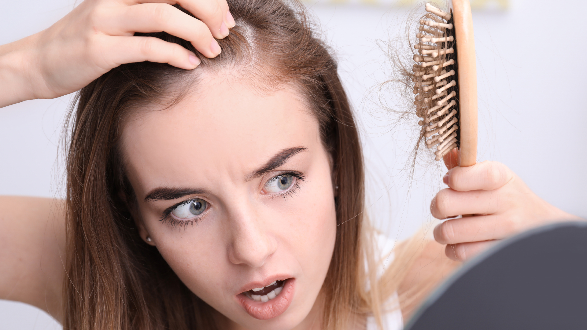 Femme tenant une brosse et examinant sa ligne frontale
