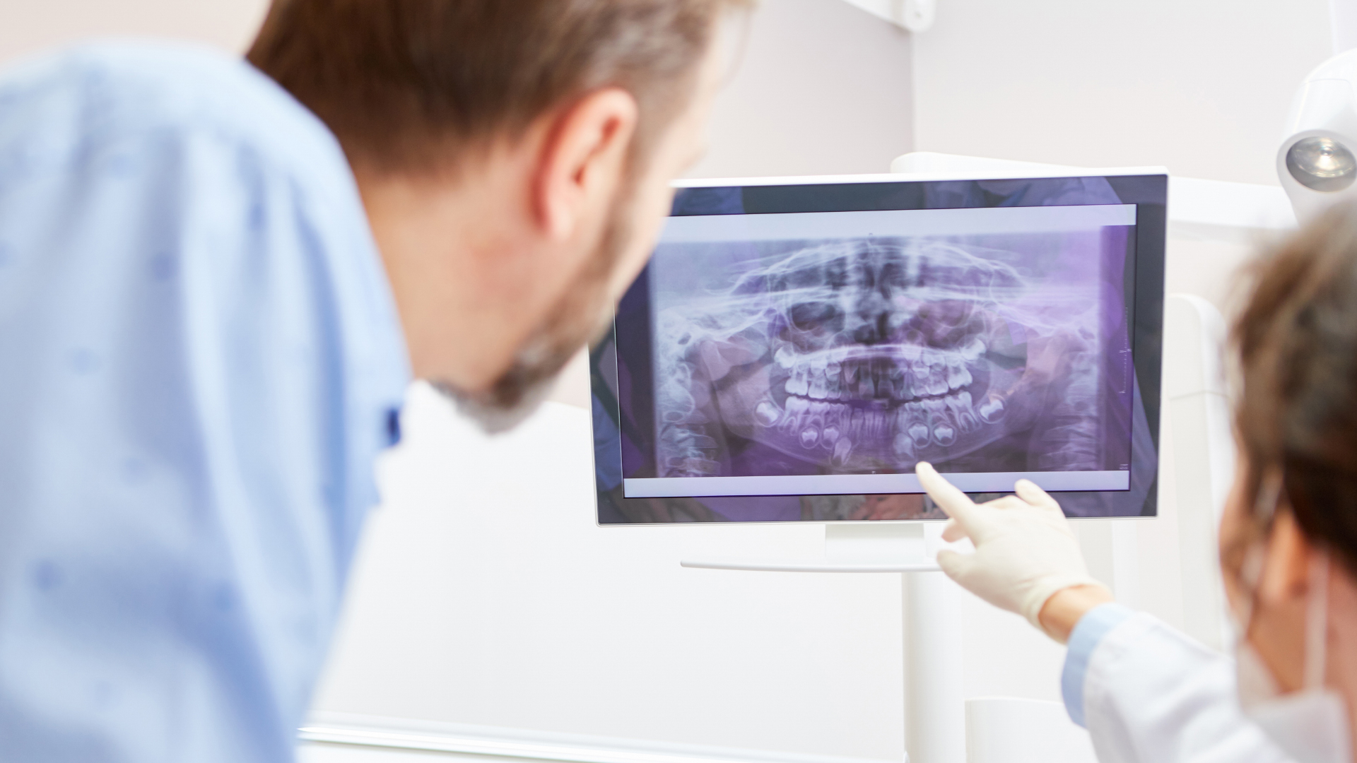 Two clinicians reviewing a panoramic dental X-ray on a screen