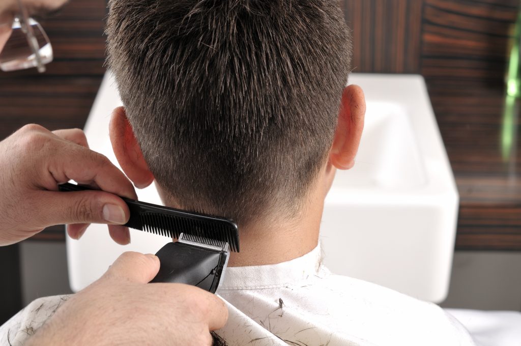 Vue de dos d’une coupe de cheveux à la tondeuse, avec un peigne noir placé contre la nuque.